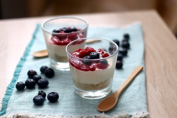 Simple no-bake raspberry cheesecake in a glass. Decorated with blueberries. Selective focus.