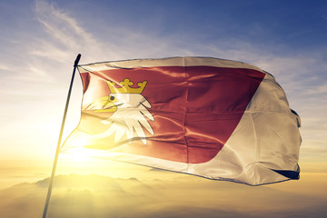 Warmian-Masurian voivodeship of Poland flag waving on the top sunrise mist fog