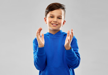 childhood, expressions and people concept - portrait of smiling little boy in blue hoodie...