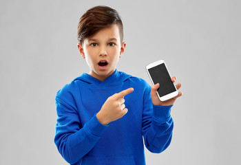 childhood, technology and people concept - shocked boy in blue hoodie showing smartphone with blank...