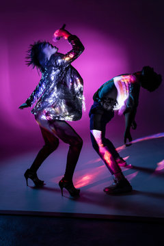 Side view of young singing lady and dancing man performing on stage under bright illumination