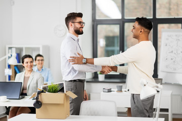 business, new job and corporate concept - male employee meeting colleague and shaking his hand at office