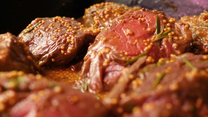 pieces tenderloin of raw beef meat marinated with mustard seeds and rosemary are lying in black tray on the store shelf in slow mo close up camera motion 4K video with no people