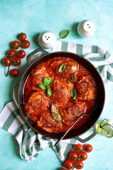 Spicy chiken legs in a tomato sauce in a skillet. Top view with copy space.