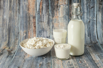 milk in a bottle sour cream cottage cheese and a glass of milk on a wooden background