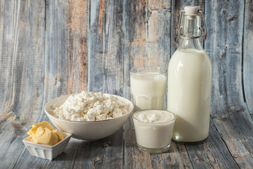 milk in a bottle butter sour cream cottage cheese and a glass of milk on a green background