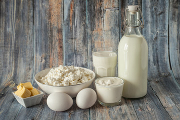 milk in a bottle eggs butter sour cream cottage cheese and a glass of milk on a green background