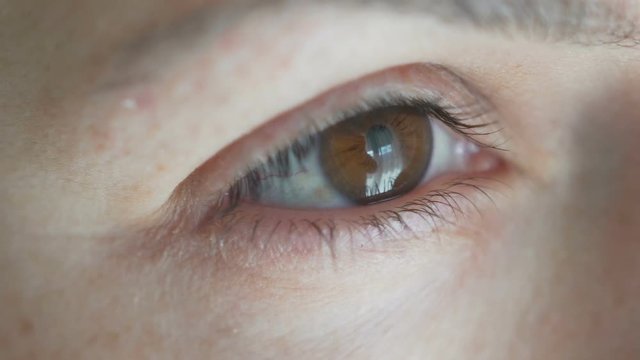 close-up opening brown female eye. squints from the light