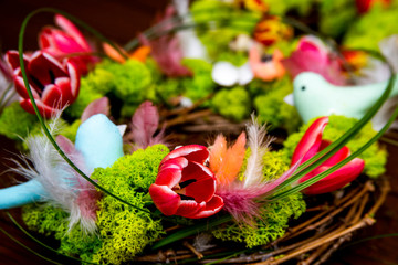 a close-up of spring tender composition of flowers, green moss, feathers and hand made birds
