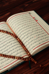 Islamic Holy Book Quran with rosary beads on wooden table background. Kuran the holy book os Muslims. Ramadan concept.