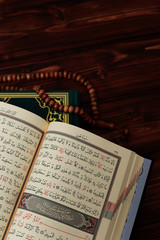 Islamic Holy Book Quran with rosary beads on wooden table background. Kuran the holy book os Muslims. Ramadan concept.