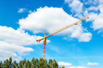 Tall yellow crane under the blue cloudy sky.