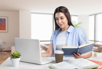Attractive young woman speaking phone and using laptop