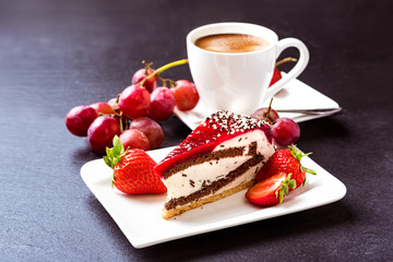 Breakfast. Dessert and coffee. A cup of hot coffee with crema, cake and fruit. Grapes, strawberries and fruit cake. Still life on a dark background