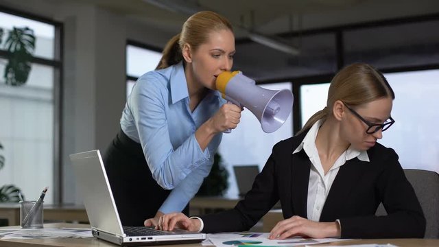 Female boss screaming with megaphone at colleague, authoritarian leadership