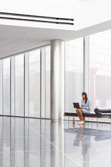 Young business woman working on laptop in industrial setting