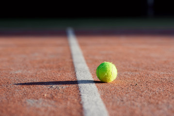 tennis rocket next to tennis ball on hard court