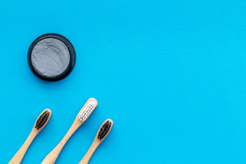 bamboo dental cleaning brush and carbon toothpaste for zero waste lifestyle concept on blue background top view mock up