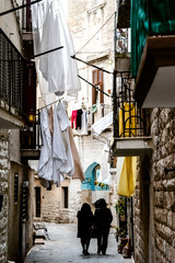 Fototapeta na wymiar Bari, Italy - March 12, 2019: People walking through the alleys of the old city of Bari.