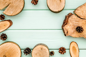 wooden sawcut and pine cone frame for blog on mint green background top view mockup