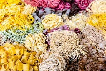 Many types of uncooked Italian pasta of various colors and shapes