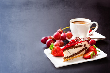 Background. Dessert and coffee. A cup of hot coffee with crema, cake and fruit. Grapes, strawberries and fruit cake. Still life on a dark background. Breakfast.