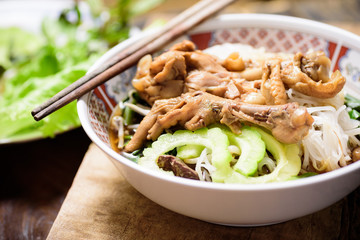 Rice noodles soup with stewed chicken wing and feet in a bowl with chopsticks