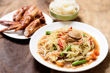 Spicy green papaya salad,grilled chicken wing and sticky rice. Thai food (Som Tum)