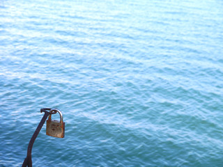 Lock locked with key next to the sea