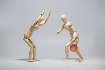 Wooden mannequin with basketball ball on gray background