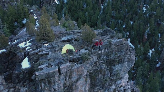 Aerial view of couple sitting on cliff ledge in there campsite rotating around as they sit on a steep ledge in American Fork Canyon in Utah.