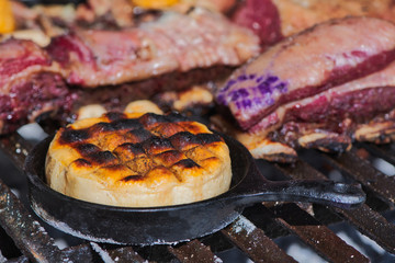 Delicious Argentinian Provolone Yarn Cheese (Provoleta) that is cooked in a cast iron skillet over the grill of a barbecue, province of Buenos Aires, Argentina. Close up scene.