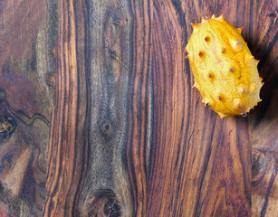 An exotic kiwano fruit on the upper right of wooden background