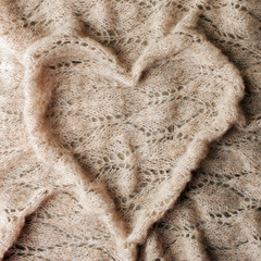 Bedding with warm plaid concept, woolen blanket in heart shape. Copy space. Flat lay, top view, monochrome background