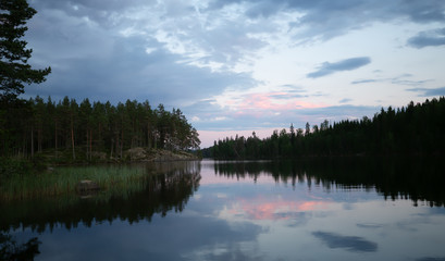 Fototapeta na wymiar Sunset over a calm lake in sweden, the clouds are reflecting on the calm surface