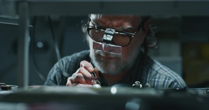 Slow motion of experienced goldsmith working on a handmade jewelry ring with precious diamond stones in a workshop. Shot in 8K. Concept of jewelry, luxury, goldsmith, diamonds, brilliance.