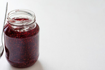 Glass jar with red jam on the table