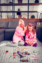 Granny and girl wearing bathrobes using hair rollers in the morning