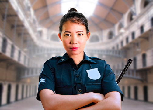 Young Serious And Attractive Asian American Guard Woman Standing At State Penitentiary Prison Hall Wearing Police Uniform In Crime Punishment