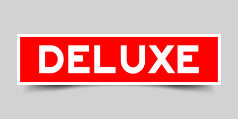 Label sticker in red color square shape as word deluxe on white background