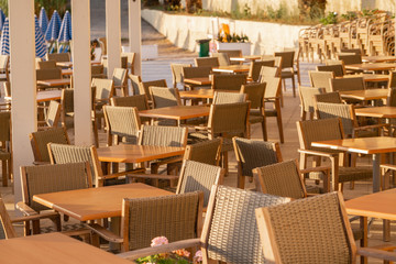 Tables in cafe. Summer sunrise on coast, Corfu island, Greece. Beach with Sunbeds and umbrellas with perfect views of the mainland Greece mountains.