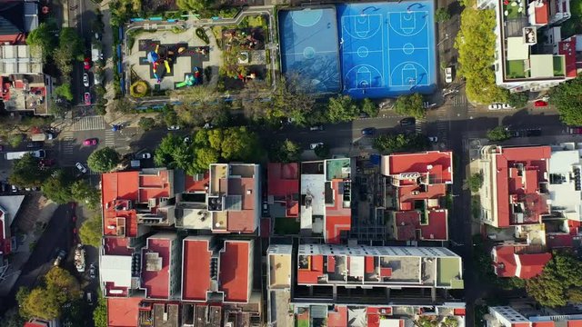 DRONE FLIGHT OVER PARK IN MEXICO CITY RESIDENTIAL AREA. KIDS PLAYGROUND COLORFUL, BLUE BASKETBALL COURT, AND CITY STABLISH
