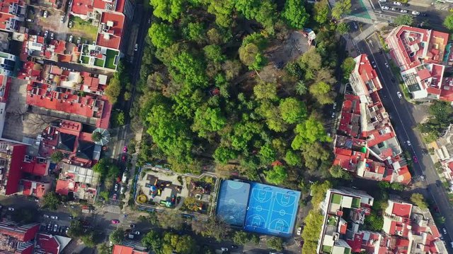 DRONE FLIGHT OVER PARK IN MEXICO CITY RESIDENTIAL AREA. KIDS PLAYGROUND COLORFUL, BLUE BASKETBALL COURT, AND CITY STABLISH