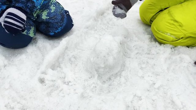 Kids playing with melting snow, making shapes of snow