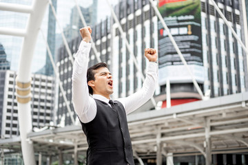 Successful business man celebrating with arms up on business district , business concept