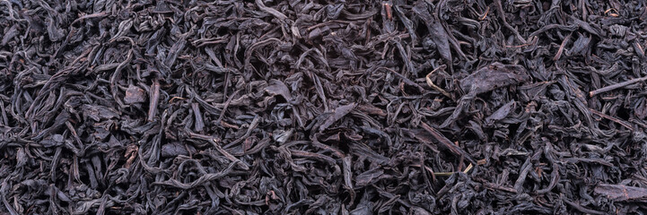 Background of dried tea leaves of dark color. Macro.