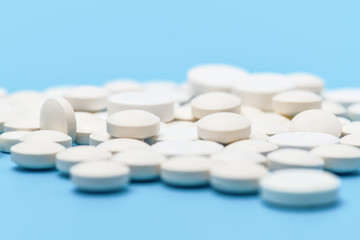 .Close-up of lots of white round pills on blue background. Medical background .