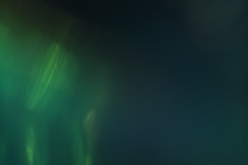 Blurred emerald green lights on dark background. Defocused lens flare glow. Bokeh effect.