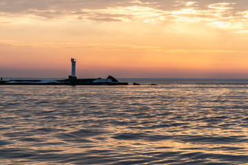 Fototapeta na wymiar маяк на берегу моря во время заката