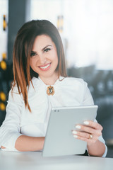 Business training. Successful female blogger. Information technology. Closeup portrait of young brunette lady sitting at desk with tablet.